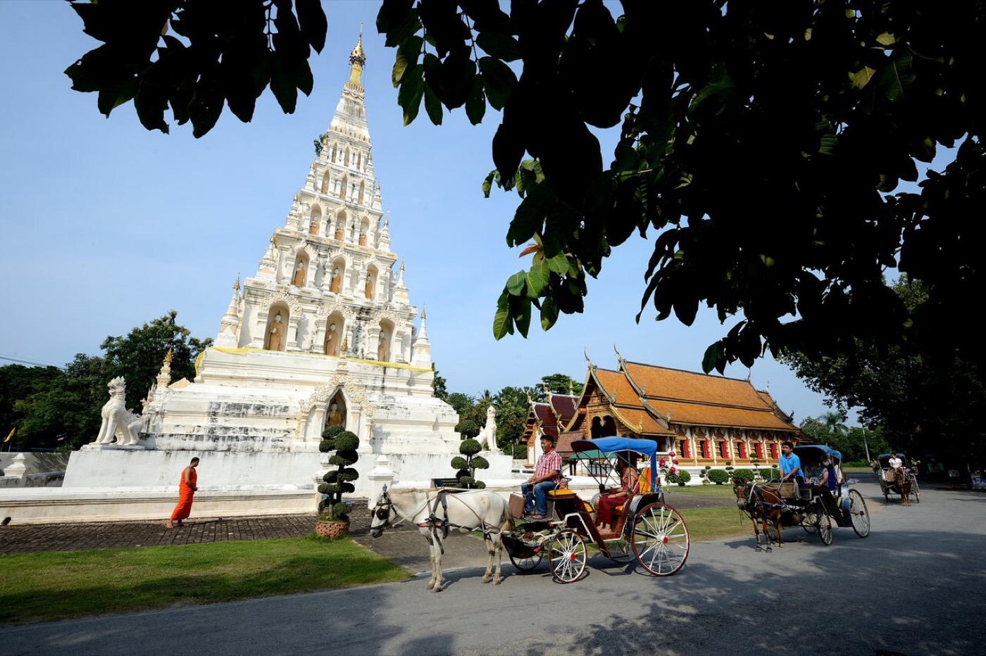 A white stepped chedi at Wiang Kum Kam with horse carts in front