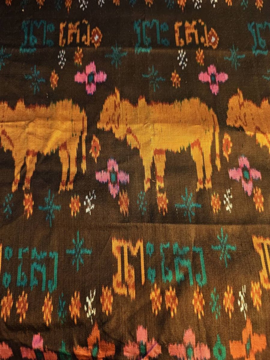 NaN's Khmer silk shawl: gold humped cattle on a dark ground, pink and teal flowers, rows of Khmer letters